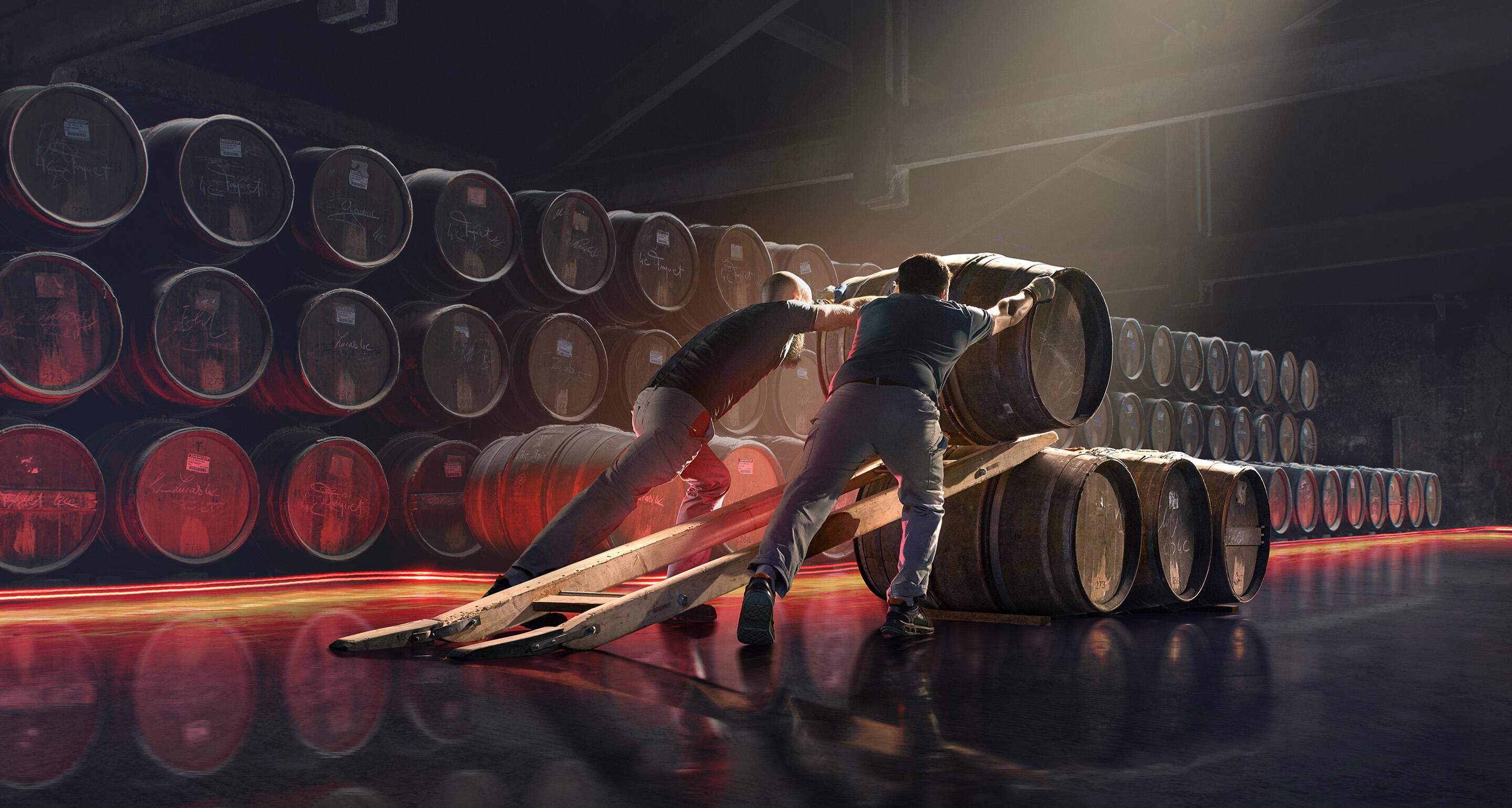 Deux agents de chais Hennessy roulent des barriques et les alignent dans des chais de vieillissement