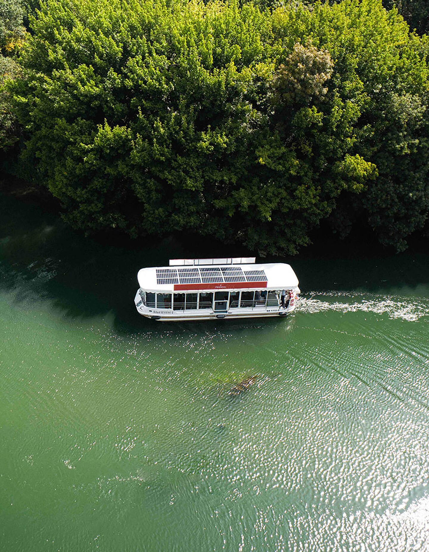 Bateau à énergie solaire Hennessy navigant sur les eaux émeraude de la Charente, à Cognac, en pleine nature