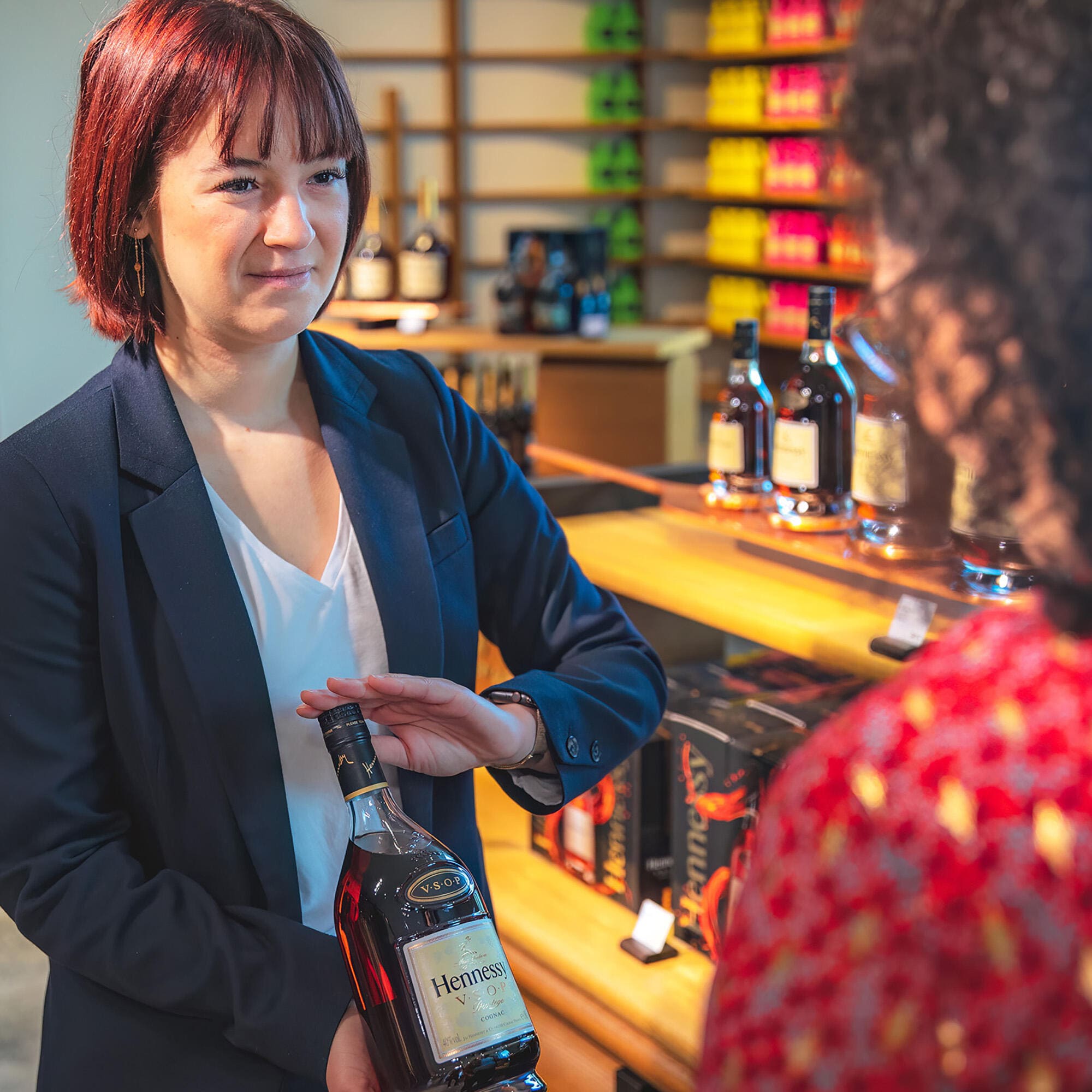Conseillère de vente à la Boutique Hennessy présentant une carafe de cognac Hennessy VSOP à une cliente