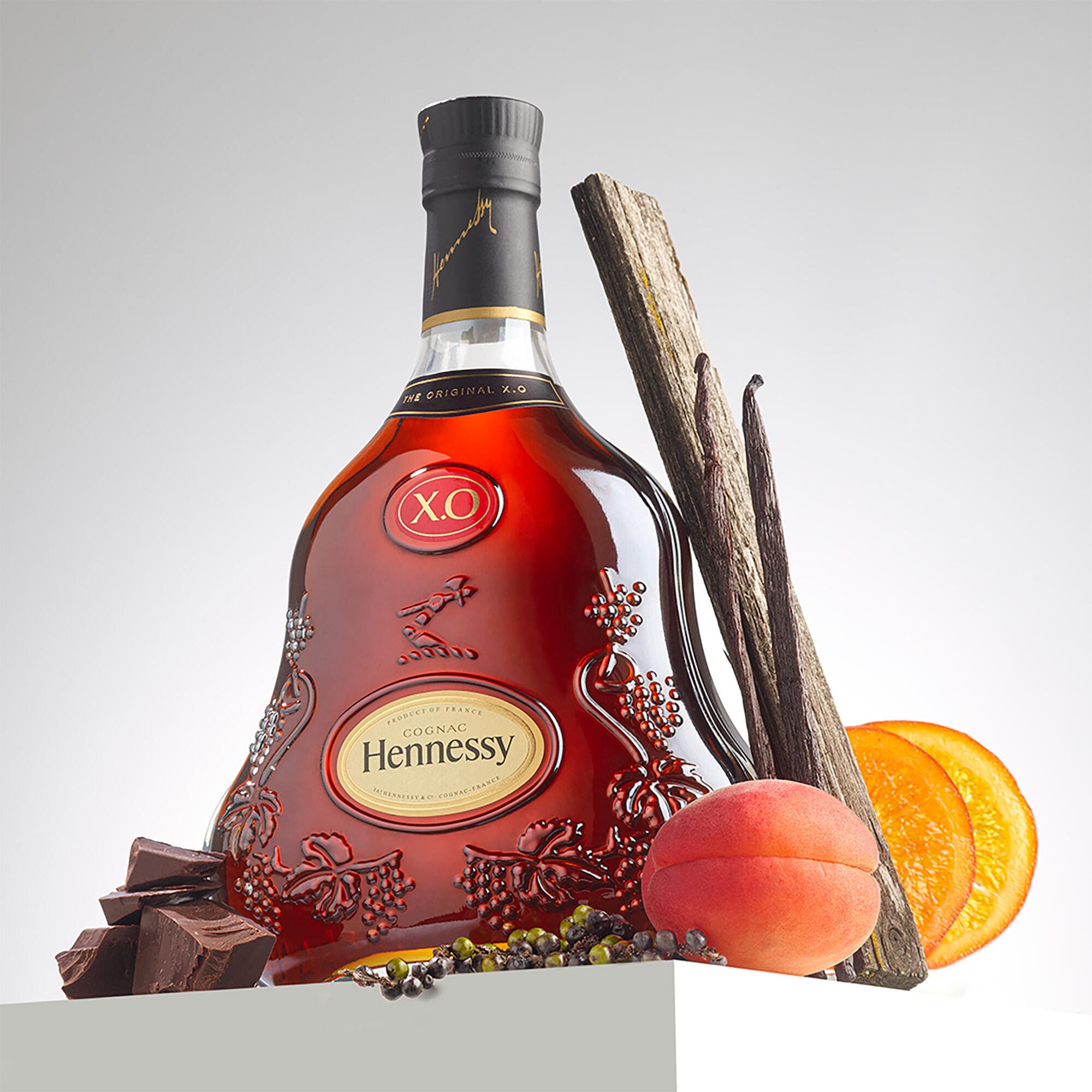 Bouteille de cognac Hennessy X.O représentée avec ses arômes principaux, tels que la vanille, l'abricot, le miel, le chocolat et l'orange confite